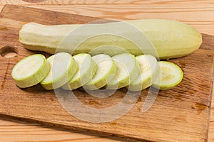 Whole and sliced light green marrows on the cutting board