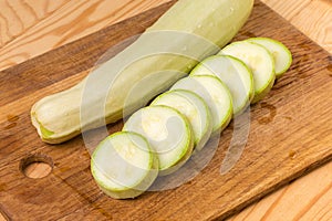 Whole and sliced light green marrows on the cutting board
