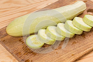 Whole and sliced light green marrows on the cutting board