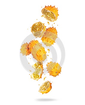 Whole and sliced ripe Kiwano melon Cucumis metuliferus in the air, isolated on white background