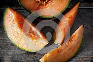 Whole and sliced ripe organic cantaloupe melon on wooden background, rustic cozy atmosphere.