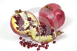 Whole and slices of red ripe pomegranate with seeds isolated on a white background. Raw organic fruits vegetables.