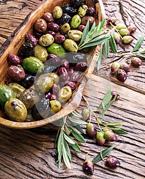 Whole table olives in the wooden bowl.