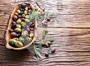 Whole table olives in the wooden bowl.