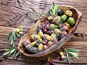 Whole table olives in the wooden bowl.