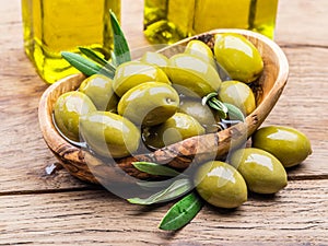 Whole table olives in the wooden bowl on the table.