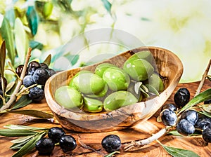 Whole table olives in the wooden bowl on the table.