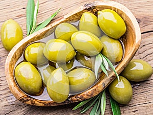 Whole table olives in the wooden bowl on the table