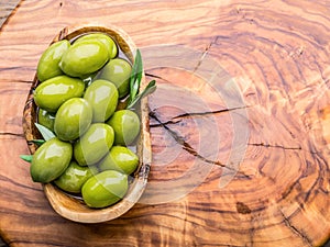 Whole table olives in the wooden bowl on the table