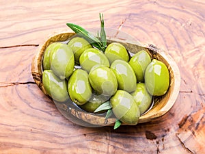 Whole table olives in the wooden bowl on the table