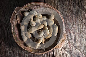 Whole tamarind fruits in wooden bowl
