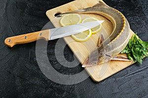 Whole uncooked sturgeon fish is on cutting board