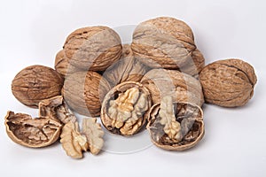 Whole unpeeled and broken walnuts on a white background.