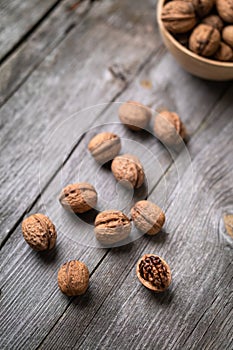 Whole walnuts in a bowl and on rustic old wooden table. photo