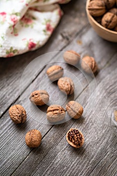 Whole walnuts in a bowl and on rustic old wooden table. photo