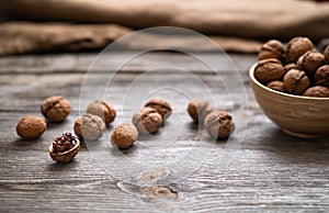 Whole walnuts in a bowl and on rustic old wooden table. photo