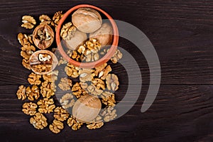 whole walnuts and kernels on wooden background, walnut on a dark old table in a clay pot