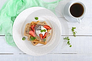 Whole wheat Belgian waffles with whipped cream, freshly chopped strawberries, mint leaves and chocolate