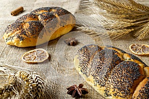Whole wheat bread. Fresh loaf of rustic traditional bread with poppy seeds, wheat grain ear on linen texture background. Rye