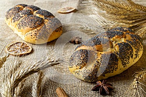 Whole wheat bread. Fresh loaf of rustic traditional bread with poppy seeds, wheat grain ear on linen texture background. Rye