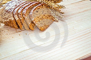 Whole wheat bread. Fresh loaf of rustic traditional bread with wheat grain ear or spike plant on wooden texture background. Rye