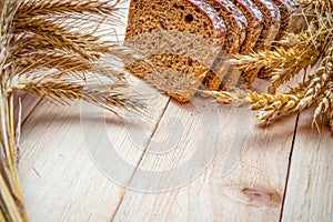 Whole wheat bread. Fresh loaf of rustic traditional bread with wheat grain ear or spike plant on wooden texture background. Rye