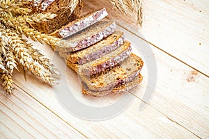 Whole wheat bread. Fresh loaf of rustic traditional bread with wheat grain ear or spike plant on wooden texture background. Rye