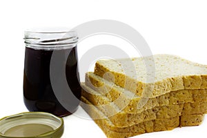Whole wheat bread stack with grape jam on isolated white background.