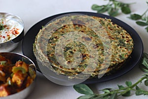 Whole wheat methi thepla rolls with paneer capsicum filling and a bowl of masala curd