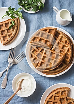 Whole wheat savory breakfast viennese waffles, cream and milk on blue background