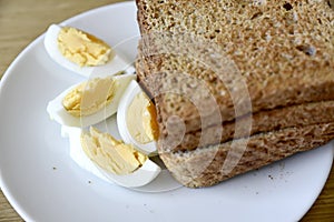 Whole wheat slice toasted bread with sliced boiled egg on the white plate for breakfast