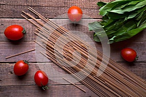 Whole wheat spaghetti with ramson and tomatoes on wood table