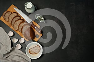 Wholegrain bread, milk, eggs and vegetable oil on a dark concrete background.