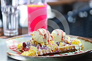 Wholegrain flour crusty belgian waffle with a scoop of ice cream and toppings. Belgian waffle with vanilla ice cream, strawberry