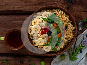 Wholegrain Oatmeal porridge bowl with fresh berries, fruits, nuts mint leaves tea cup. Healthy food oat meal breakfast