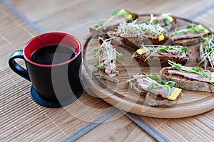 Wholegrain sandwiches with micro greens and morning coffee cup. Vegan party food table with organic vegetables canapes