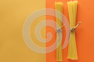 Wholegrain spaghetti on a bright yellow and orange background. Top view. Place the text
