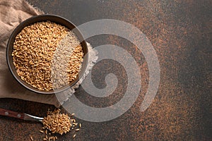 Wholegrain spelt farro in wooden bowl on brown background. Top view. Copy space