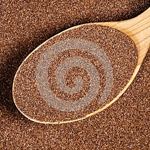 Wholegrain teff seeds in wood spoon closeup