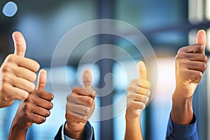 We wholeheartedly approve. a group of businesspeople giving thumbs up in a modern office. photo