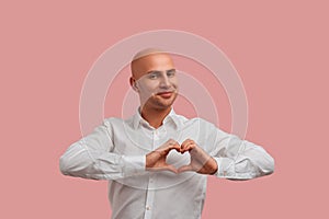 Wholeheartedly. Happy bald man with bristle in white shirt, holds fingers in heart gesture. Shows his love and pure photo