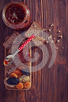 Wholemeal bread with apricot jam surrounded by dry fruit. Vintage/Retro style.