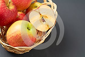 Wholes, one half of red fresh ripe apples full of vitamins lies in wooden wicker basket