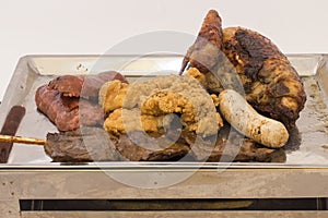 Wholesome metal platter of mixed meats including grilled steak., pork, chicken, sausage, beef heart on a stick