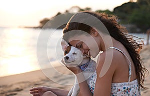 Whos a good boy. an attractive young woman petting her dog at the beach.