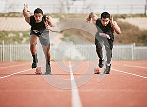 Whos got the pace. Full length shot of two handsome young male athletes starting their race on a track.