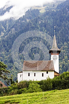 Whte chapel on the high hill with forest at the background