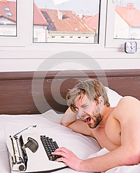 Why author use manual typewriter daily work. Man writer lay bed white bedclothes working on new book. Writer author used