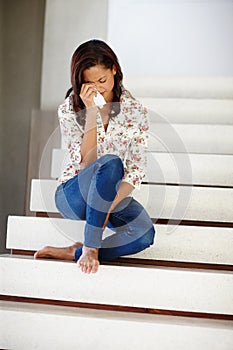 Why did he break up with me. A young woman sobbing on the staircase.