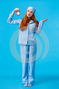 Why didnt you set alarm. Confused and unsure upset attractive redhead woman in pyjama and sleep mask, shrugging